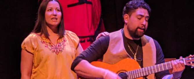 actors on stage singing with guitar