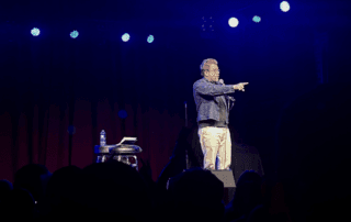 comedian Adam Conover on stage in Denver