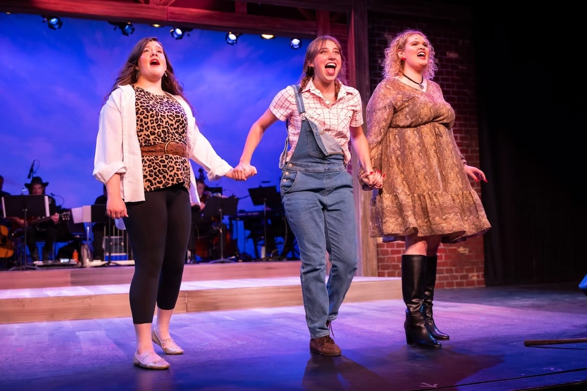 Three woman sing and hold hands