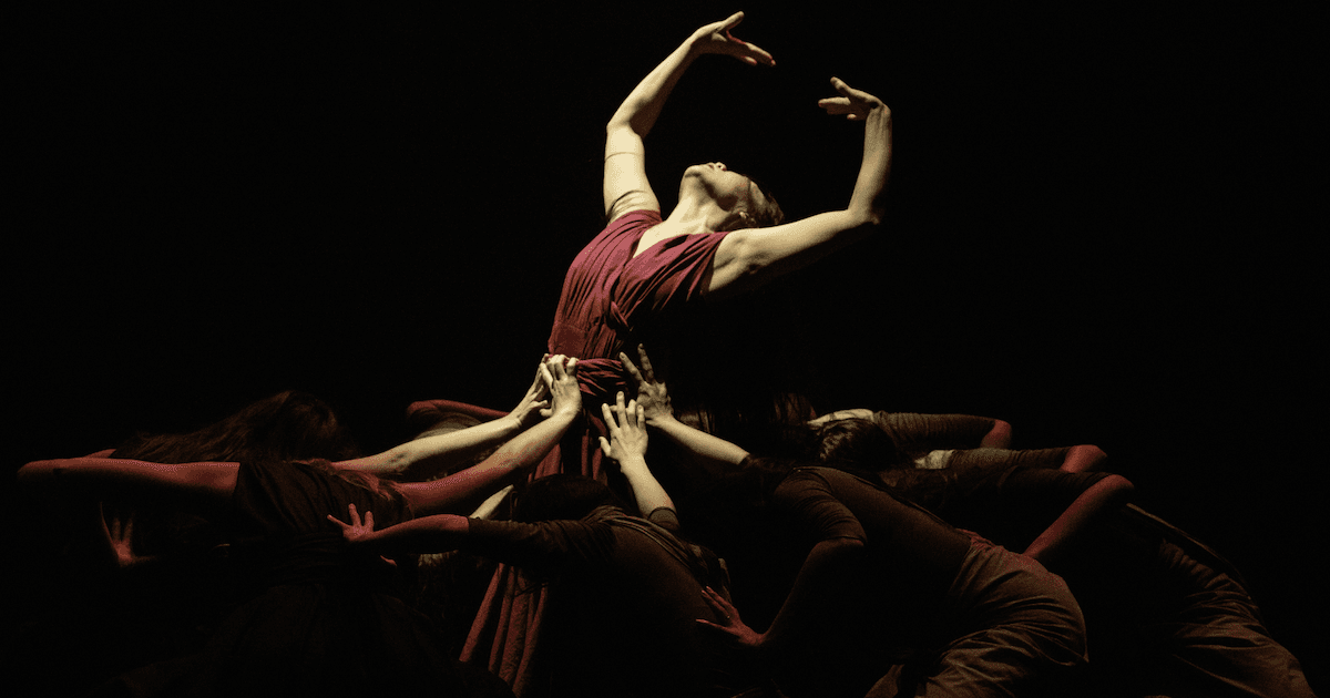 A woman is supported by her fellow dancers