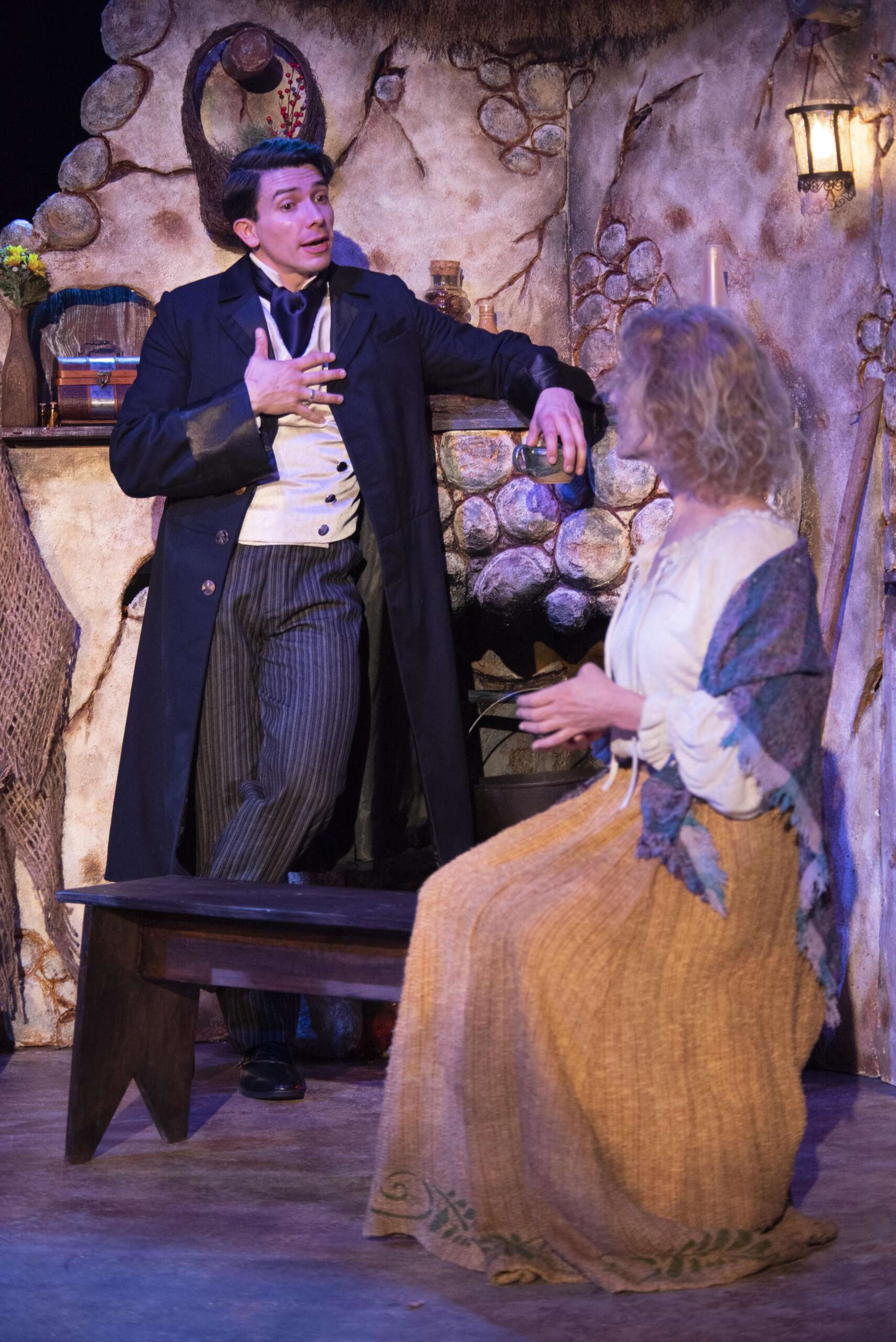 A man stands and talks to a woman who is seated