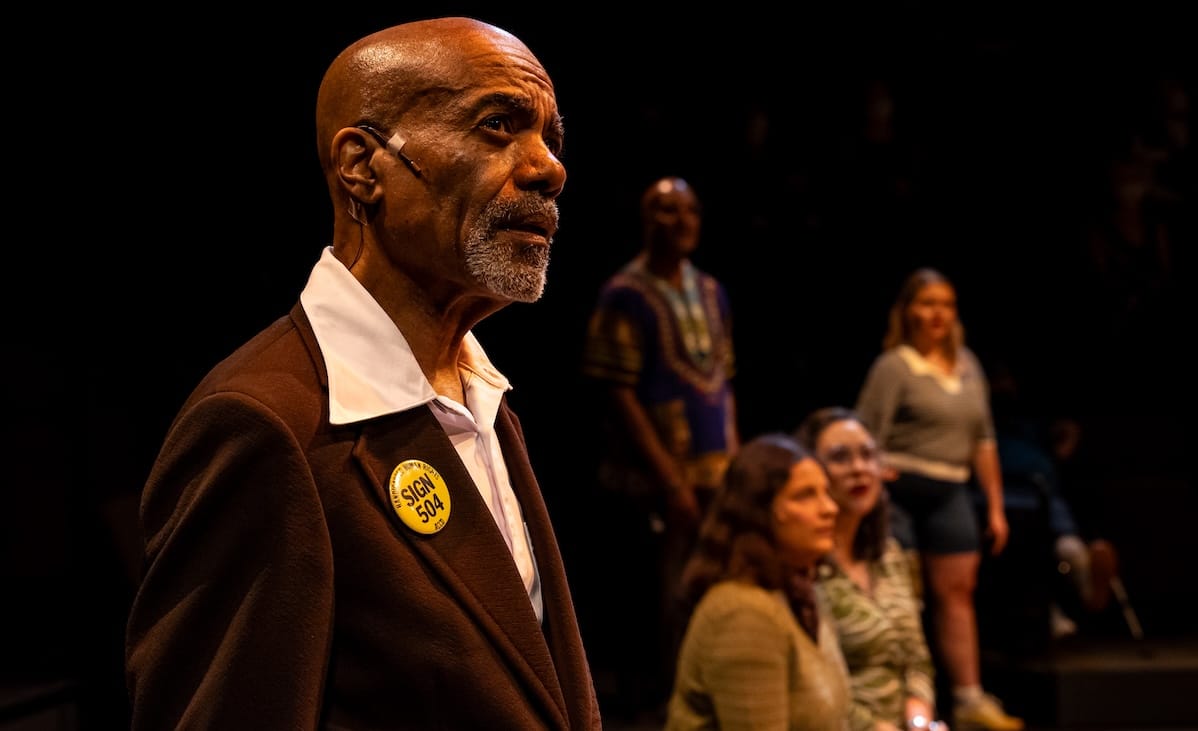 '504: The Musical' sings the messy work of solidarity 3 A man looks off into the distance with others in the background