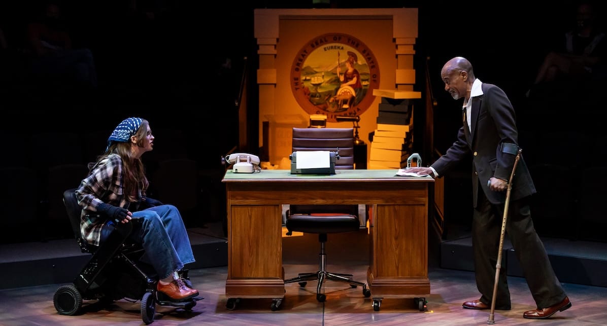 '504: The Musical' sings the messy work of solidarity 4 A person in a wheelchair and a man with an arm crutch in a government building