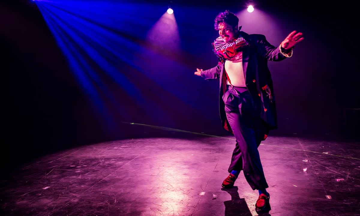 A dressed as a clown dances onstage