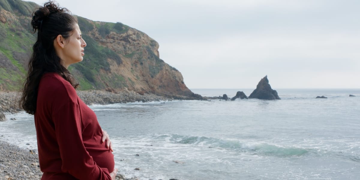 HOLDTIGHT's 'mother : un/tethered' shifts from stage to screen 2 A pregnant woman stands by the ocean in