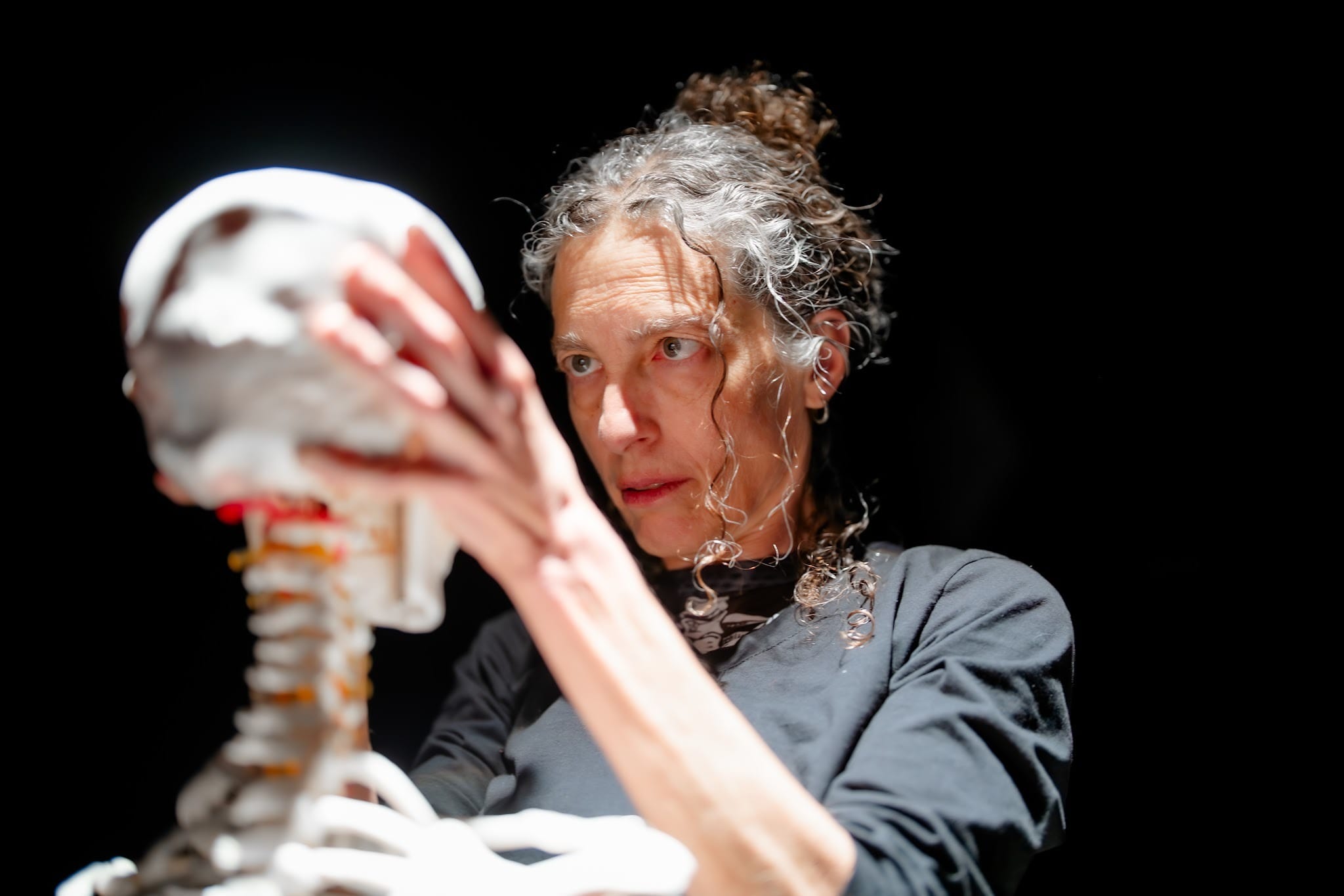 A woman holds the head of a skeleton in a play called No Contract