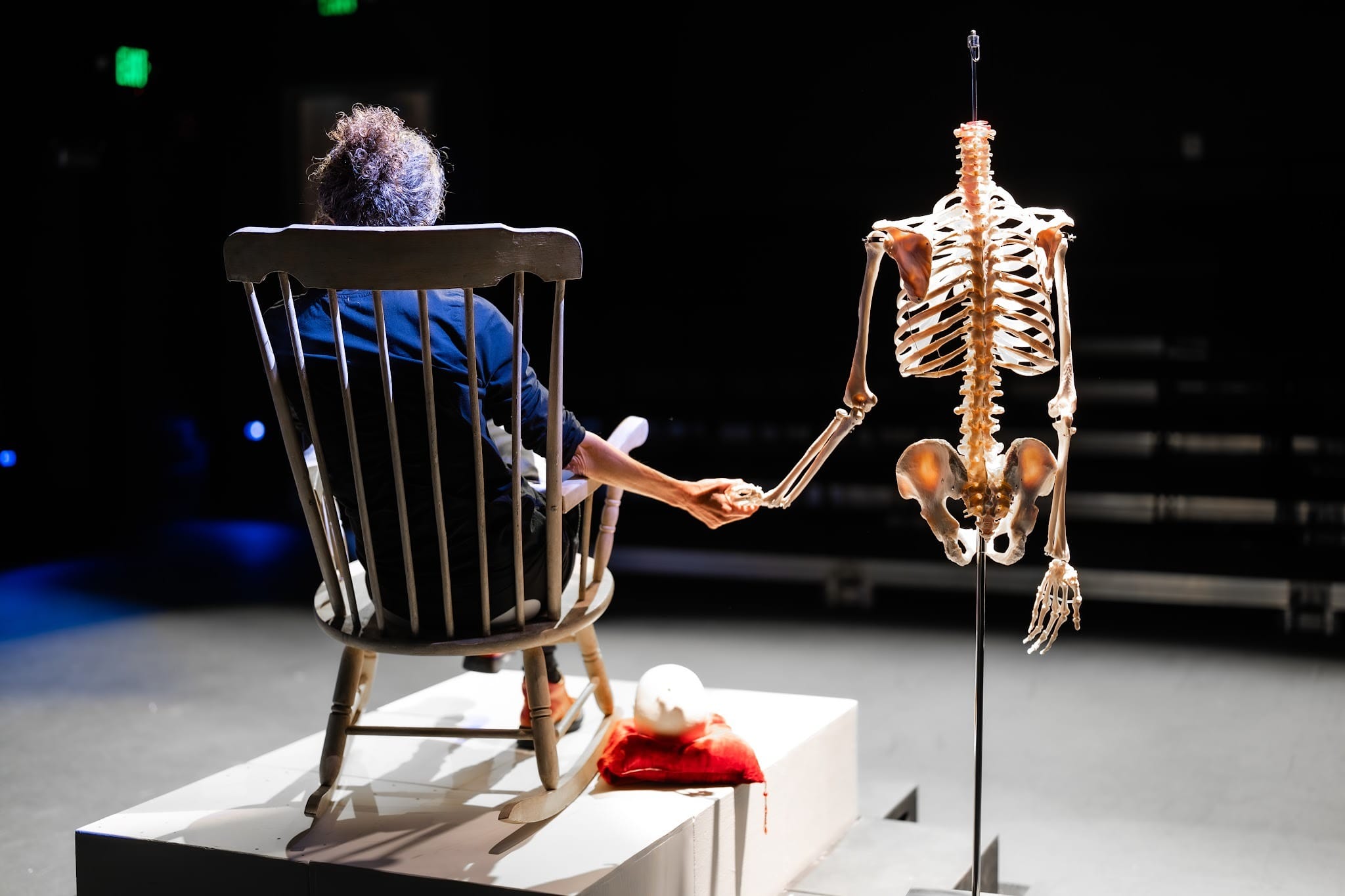 A woman holds hands with a skeleton in a play called No Contract