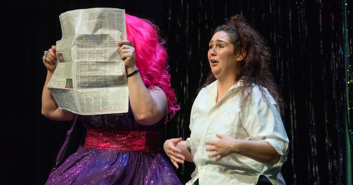 Local Theater experiments with world premiere of ‘Drag Queen Magic’ 2 A drag queen holds a newspaper over her face while a woman talks